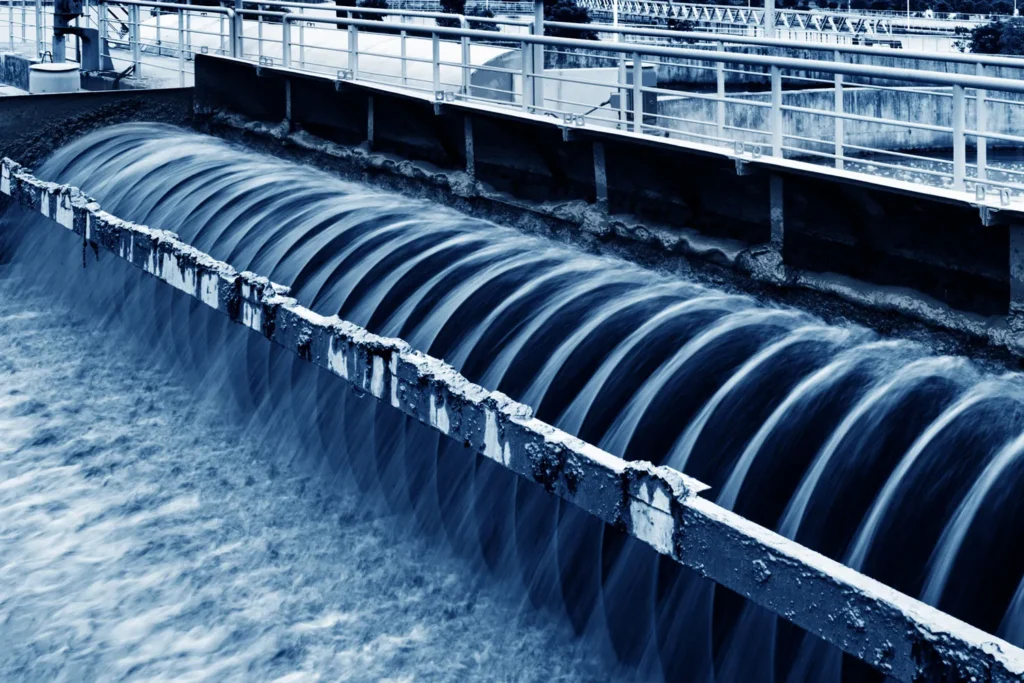 Water flows over a series of curved spillways at an industrial water treatment facility, creating a cascading effect.