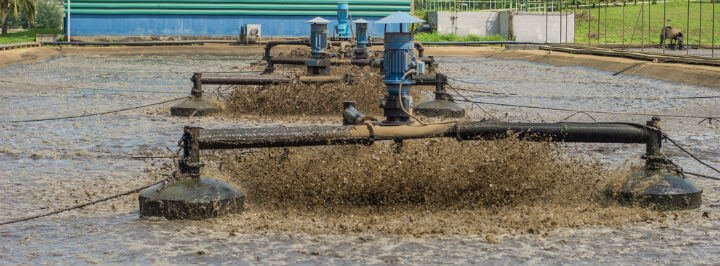 Aerators churning and splashing wastewater in a treatment plant, processing sewage for purification and environmental compliance.