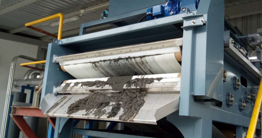 Industrial filter press machine processing sludge in a factory setting.
