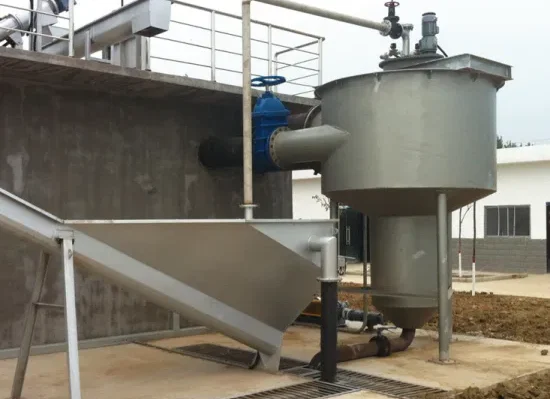 Industrial grit trap system with large metal components at a facility site, featuring pipes and a sedimentation tank.