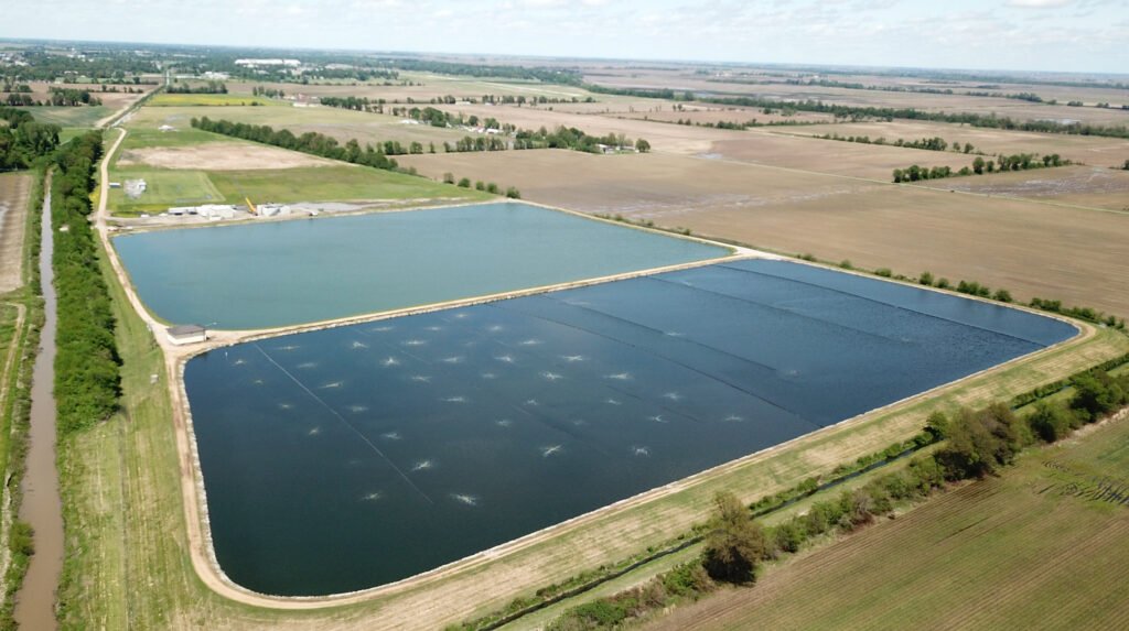 Aerial view of two large rectangular aquaculture ponds surrounded by fields and a few scattered buildings.