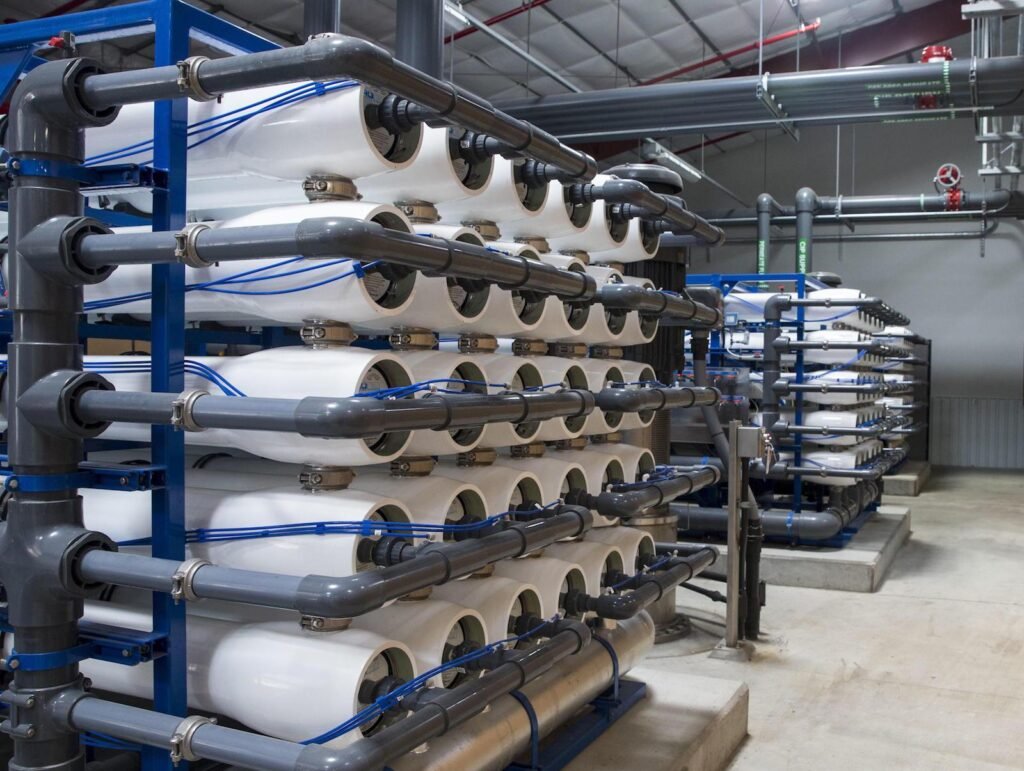 Rows of cylindrical reverse osmosis filter membranes in an industrial water treatment facility with connecting pipes and valves.
