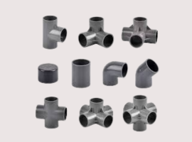 Various PVC pipe fittings, including elbows, tees, caps, and crosses, arranged in rows on a light background.