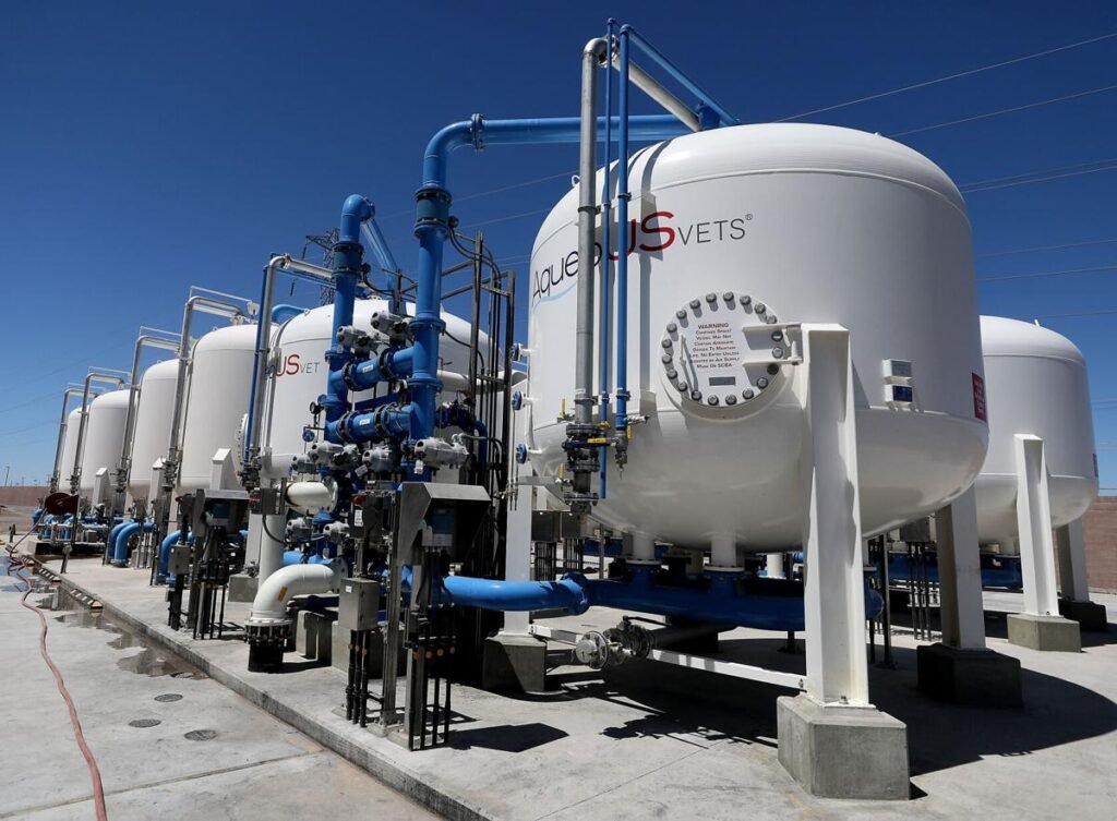 Large white industrial tanks with intricate blue and black piping stand outdoors against a clear blue sky, resembling a distribution system. This impressive setup seems integral to Tucson Water's effort in managing reclaimed water.