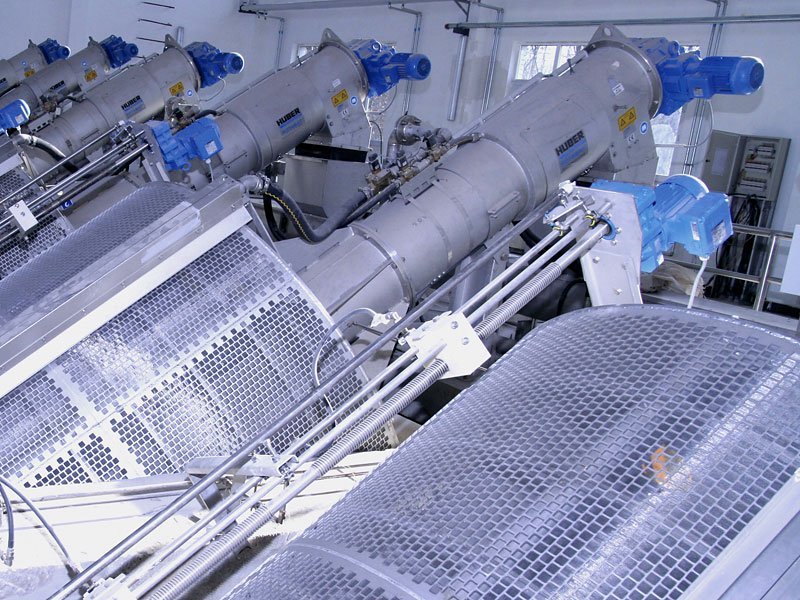 Industrial wastewater treatment machinery with cylindrical screens and pipes in a facility.