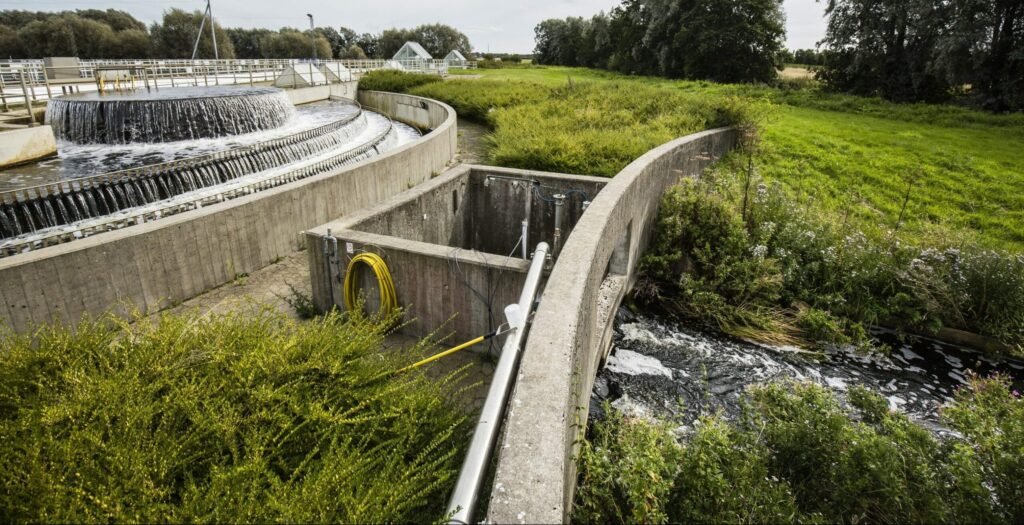 A water treatment plant with cascading water feature, surrounded by lush greenery and a rural landscape.