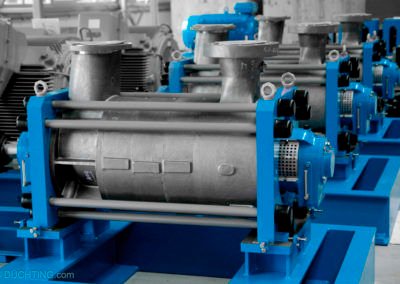 Image of industrial machinery with multiple blue and metallic pumps, including high-pressure centrifugal options, aligned in a row. The equipment features cylindrical components and various pipes, providing efficient solutions for industrial applications in a factory setting.